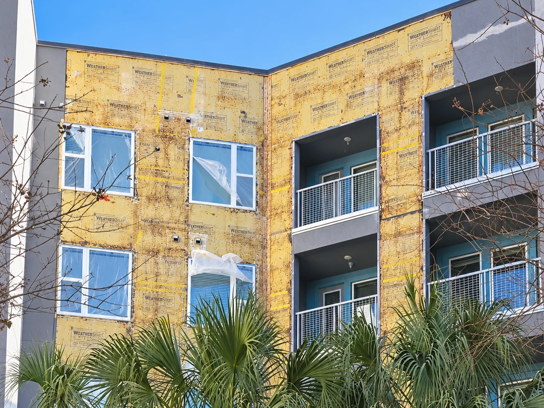 Mid rise apartment building with old stucco removed to the weather barrier during repair by ZLS Contractors in Maitland FL