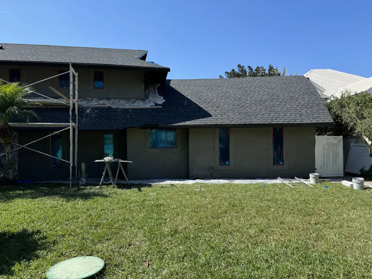 New stucco base coat applied across a two story home during repair by ZLS Contractors